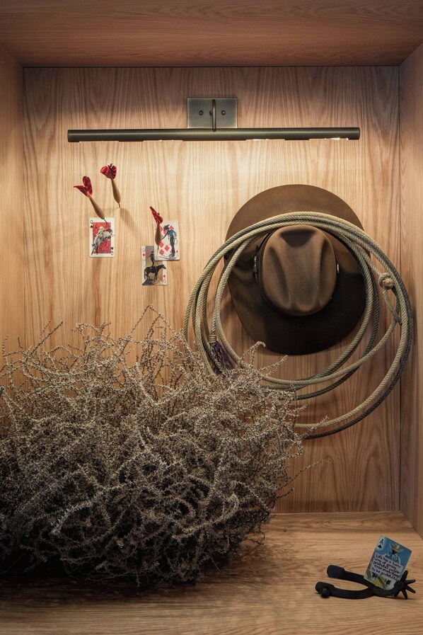 A wooden wall with a mounted rope, a hat, and playing cards.