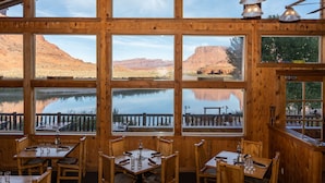 Un restaurant doté de grandes fenêtres offrant une vue sur un lac et des montagnes.