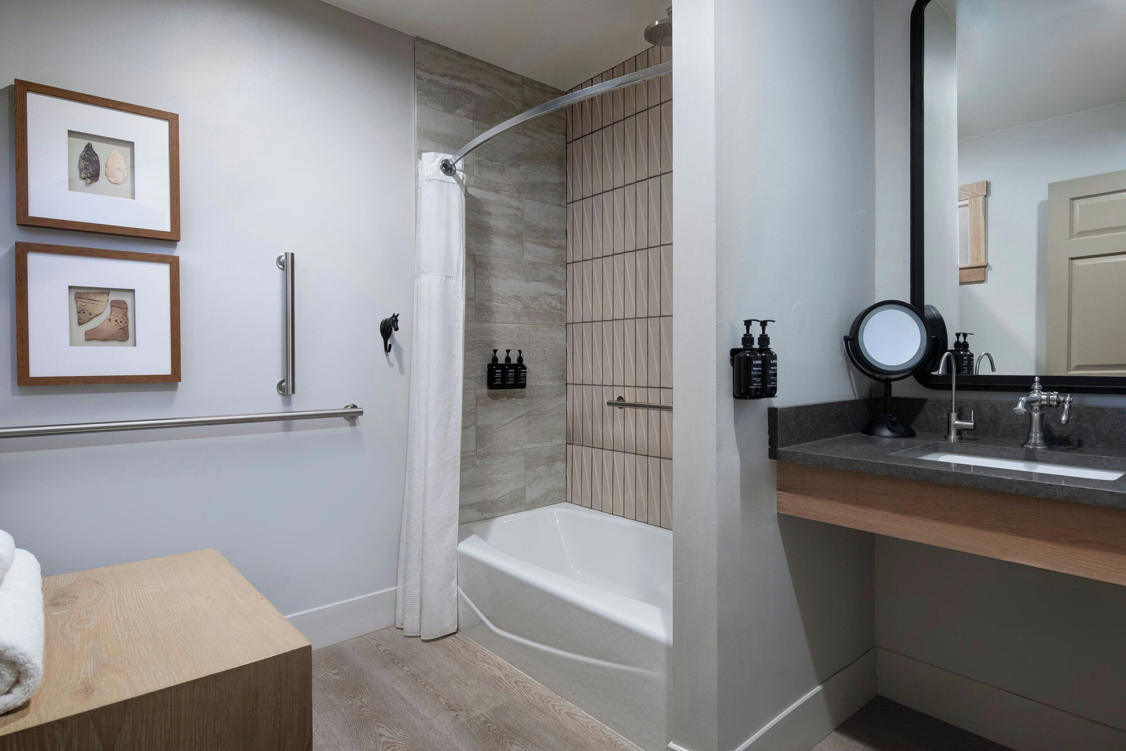 A modern bathroom with a shower, a bathtub, a vanity with a sink, and two framed pictures on the wall.