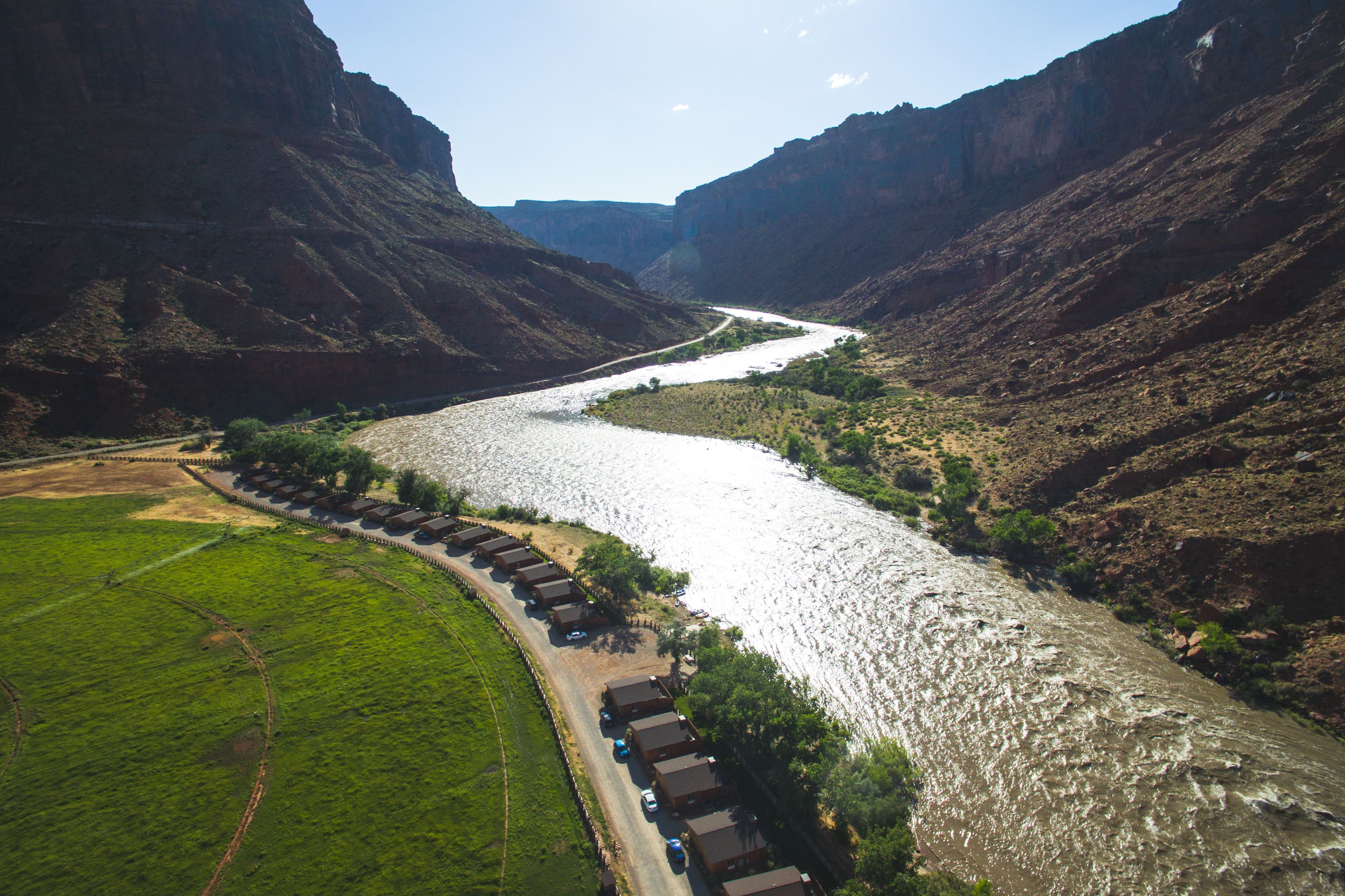 A river winding through a canyon with a row of cabins along the riverbank.