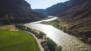 A river winding through a canyon with a row of cabins along the riverbank.