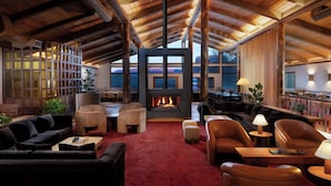Un vaste espace de vie agrémenté d’une cheminée, de poutres apparentes en bois et de sièges confortables.