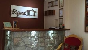 Un área de recepción con mostrador de piedra, una silla tapizada en rojo y un cartel que dice "El jacal".