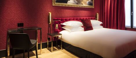 A hotel room with a large bed, a desk, and a chair.