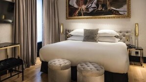 Un dormitorio moderno con una cama grande, dos otomanas, un escritorio y un televisor.