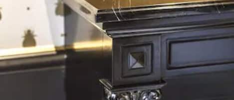 Un comptoir en marbre noir, agrémenté d’une colonne décorative et d’un mur orné d’un motif de scarabées bruns.