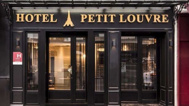 Fachada negra del Hotel Petit Louvre con el logotipo de la Torre Eiffel sobre la entrada.