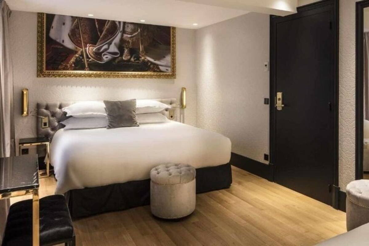 Una habitación de hotel moderna con una cama grande, un escritorio y un cuadro en la pared.