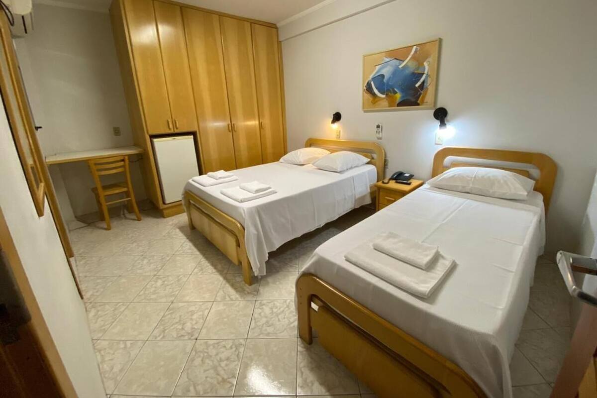 Ein Hotelzimmer mit zwei Betten, einem Schreibtisch und einem Kleiderschrank.