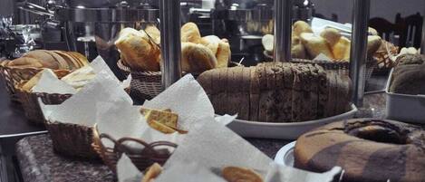 A bakery display with various baked goods, including bread and cakes, arranged on a counter.