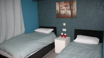 A bedroom with two beds, a nightstand, and a painting on the wall.
