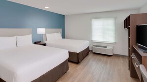 A hotel room with two beds, a TV, a desk, and a window with blinds. - WoodSpring Suites Bakersfield East (Bakersfield)