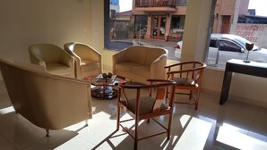 Una habitación de hotel con un ventanal grande, un sofá, dos sillones y una mesita de centro.