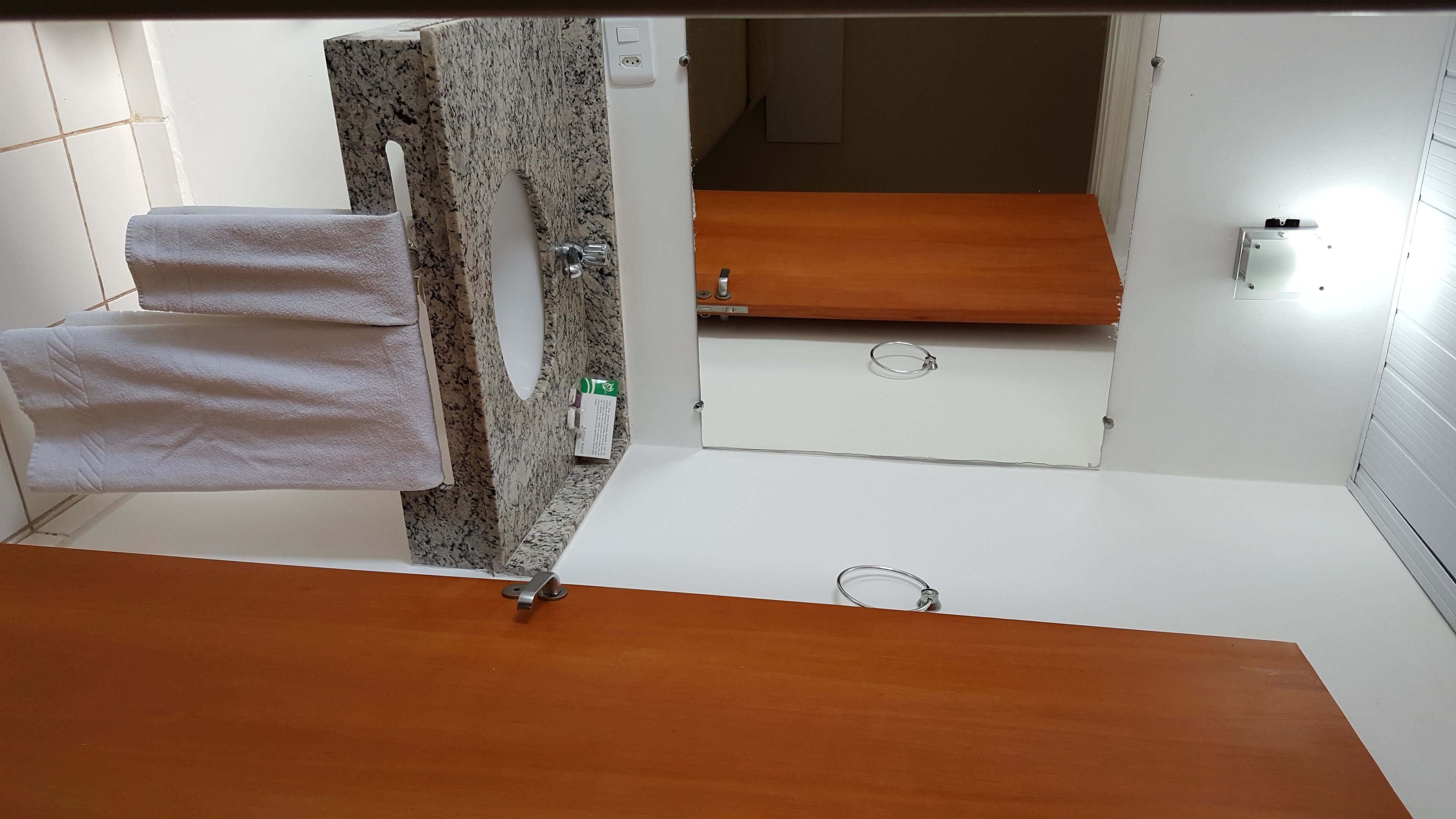 Een badkamer met een houten wastafelmeubel, een handdoekhouder en een spiegel.