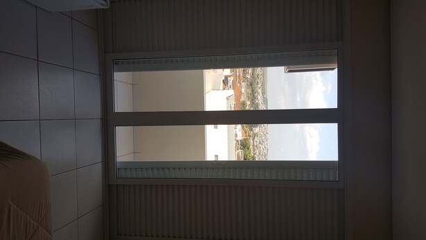 Una habitación con un ventanal grande, suelo de baldosas y un radiador.