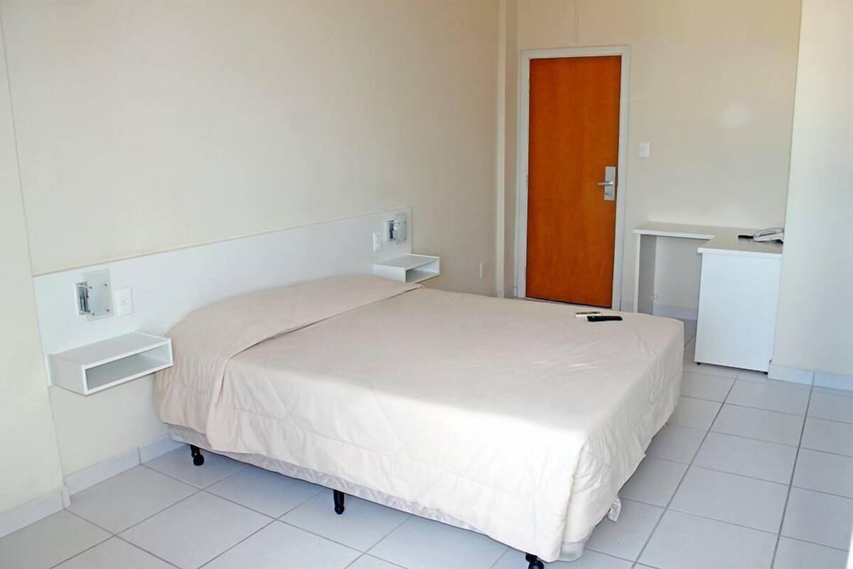 Une chambre à coucher comprenant un lit, des tables de chevet, une armoire et un bureau.