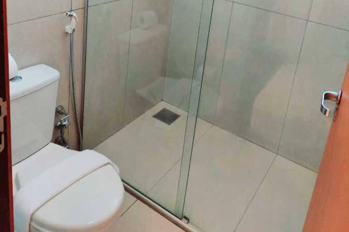 A glass-enclosed shower stall with a toilet to the left.