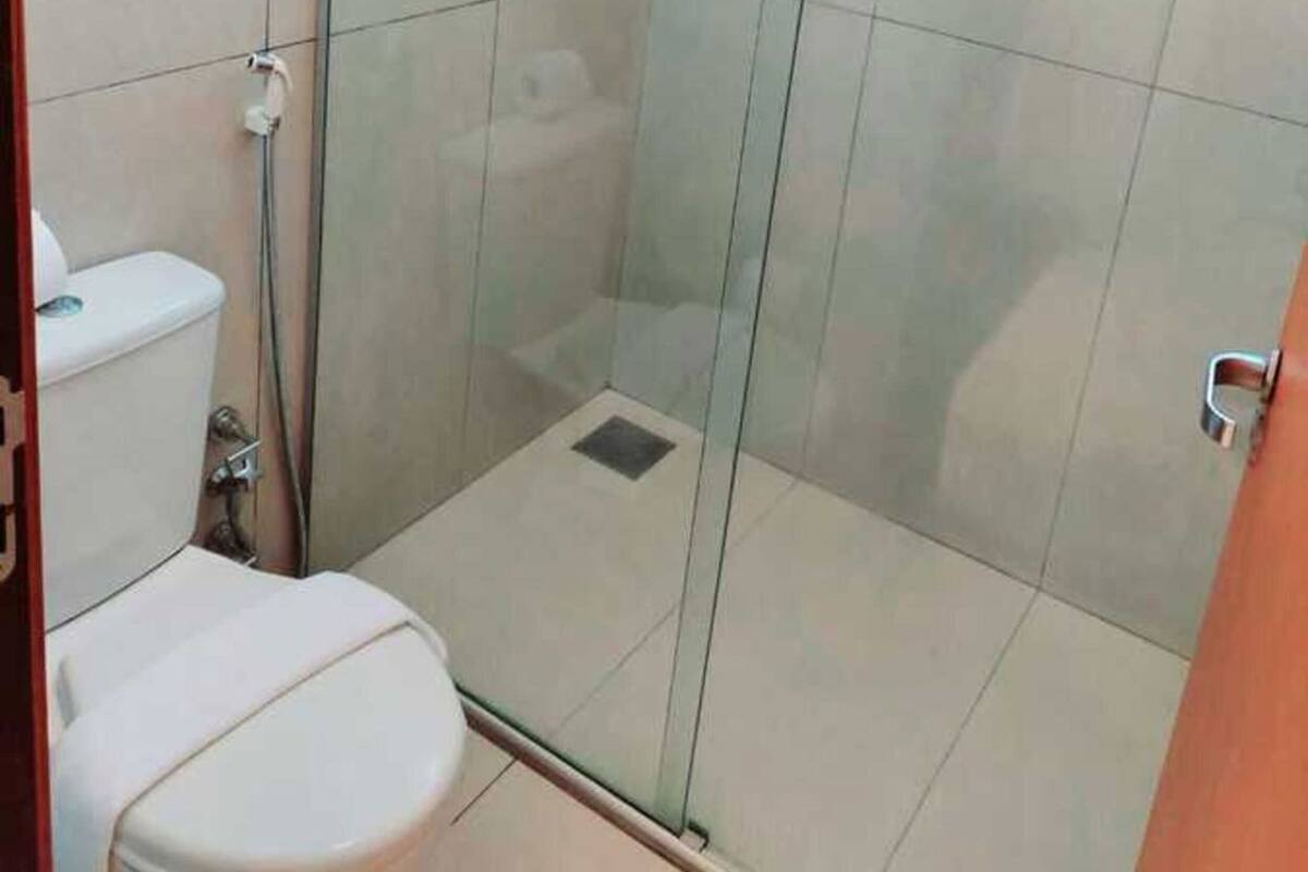 A bathroom with a glass-enclosed shower, a toilet, and a sink.