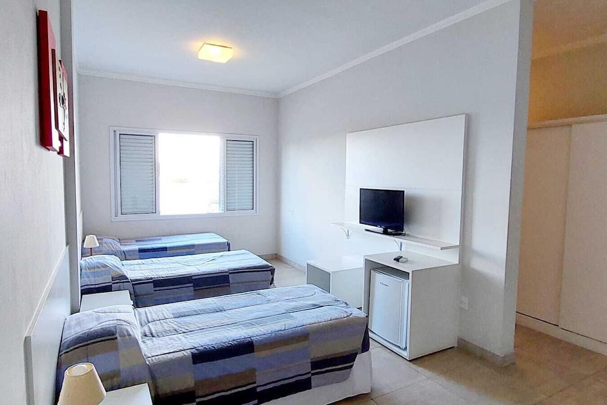 A small, clean room with two beds, a desk with a computer, and a TV.