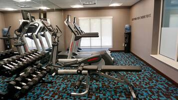 Un gimnasio con cintas de correr, elípticas y pesas.