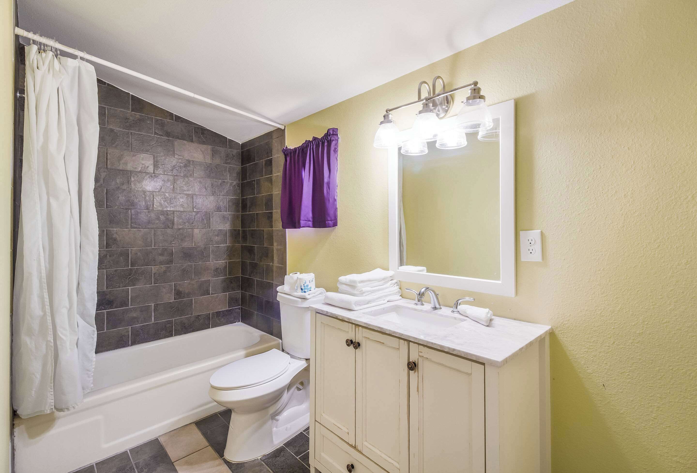 A bathroom with a bathtub, toilet, and vanity with a mirror.