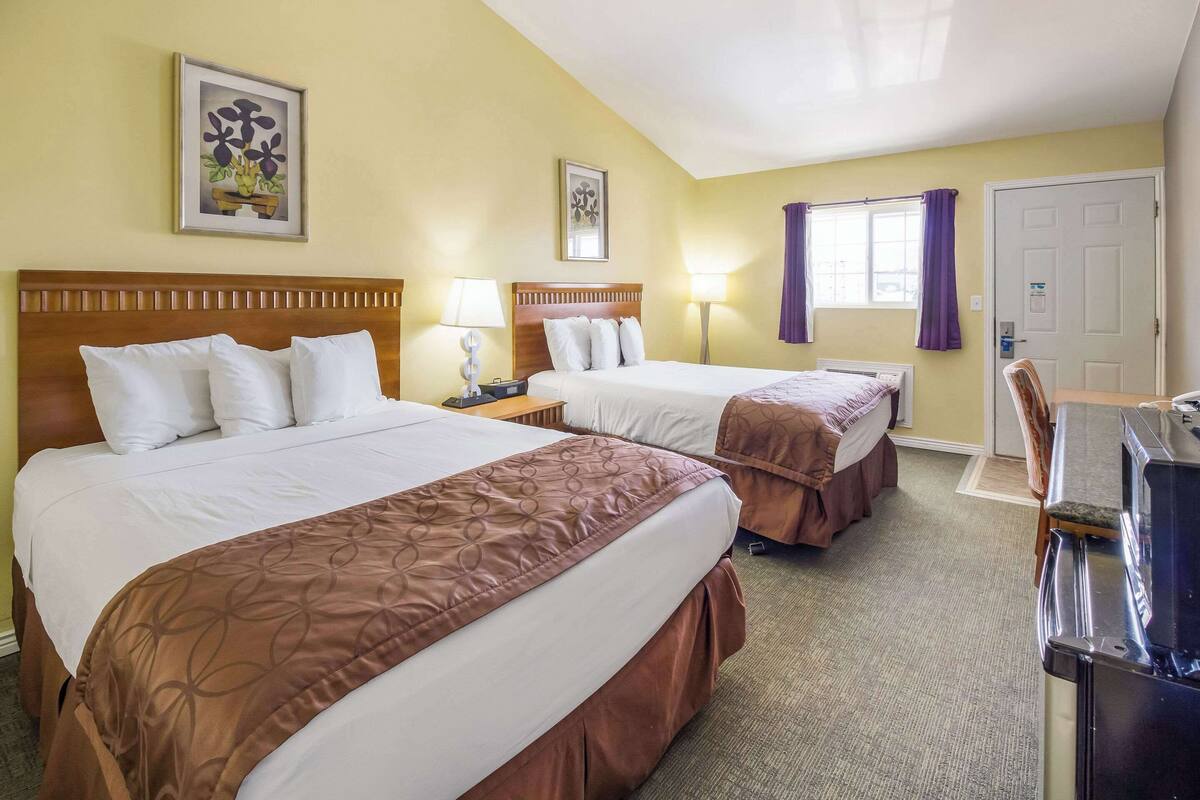A hotel room with two beds, a desk, and a chair.
