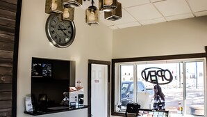 L'intérieur d'un magasin avec une horloge, des étagères et une vue sur la rue par la fenêtre.