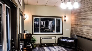 Une pièce dotée d’une grande fenêtre, d’une machine à café, d’un radiateur, d’un canapé et d’un mur en bois.