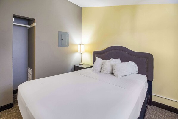 Una habitación de hotel con una cama grande, una lámpara de noche y una puerta.