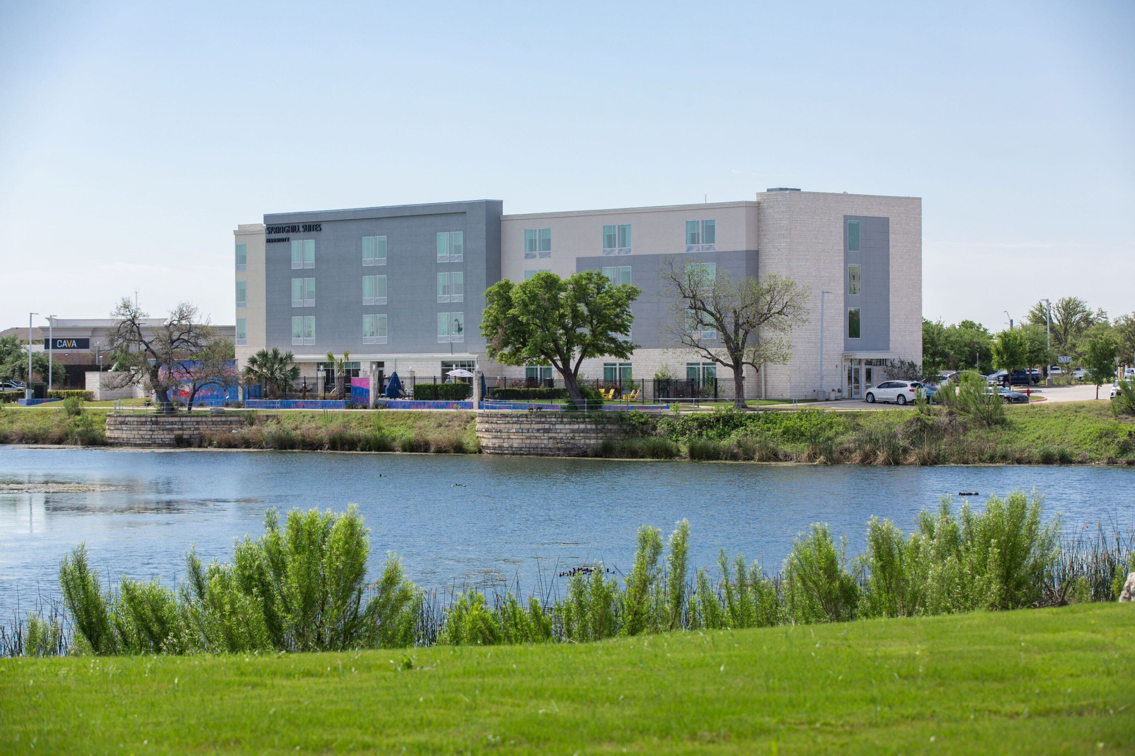 Un hotel moderno con un edificio grande y un lago frente a él.