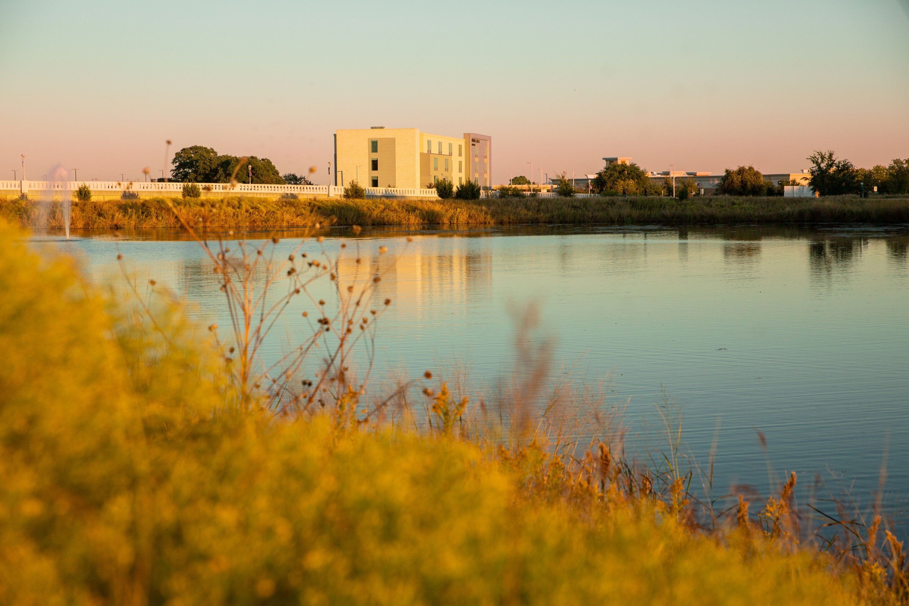 Un lago tranquilo con un edificio al fondo.