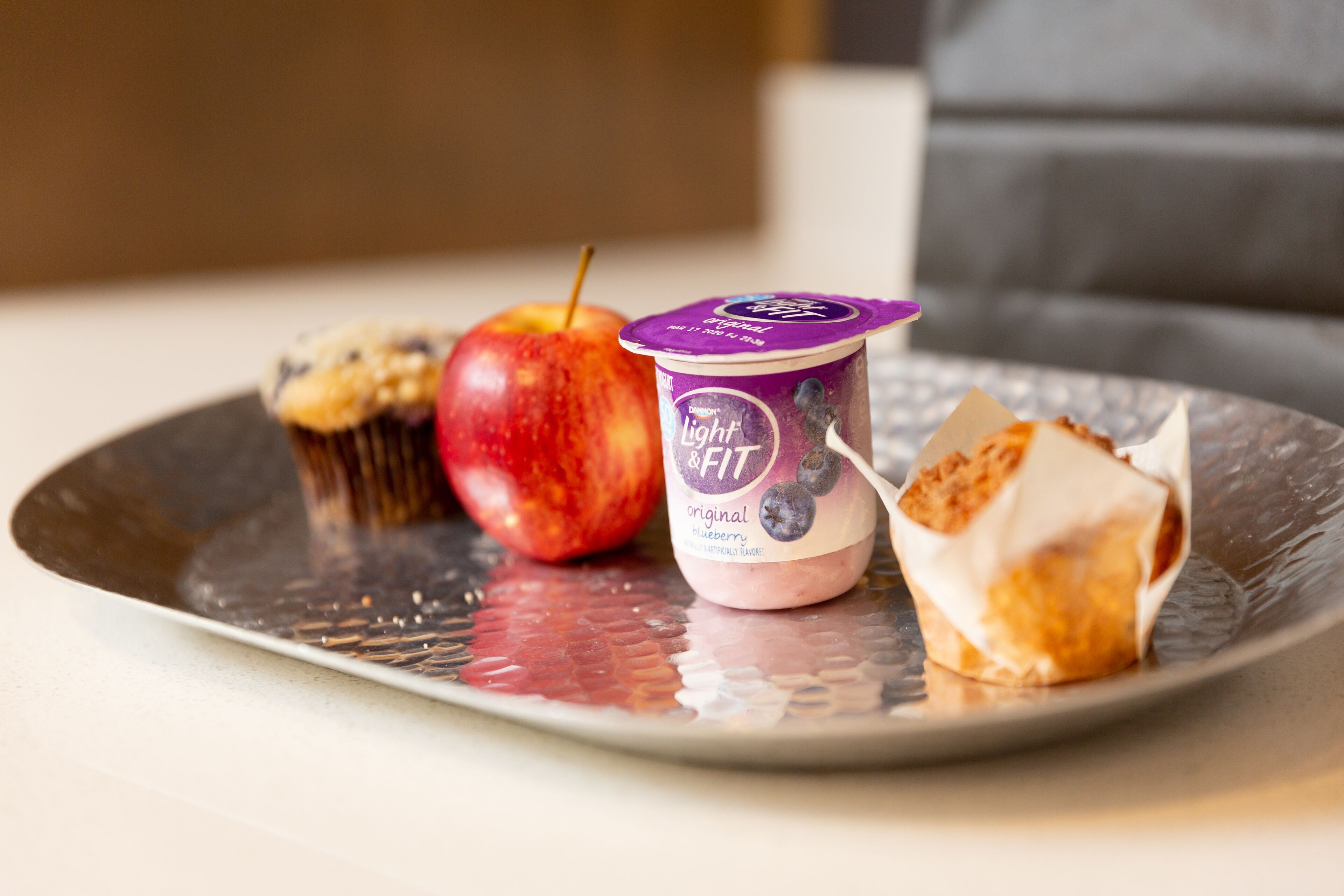 En tallerken med yoghurt, et æble og en muffin.