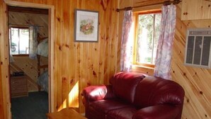 A wooden cabin interior with a red leather couch, a wooden table, and a framed picture on the wall.
