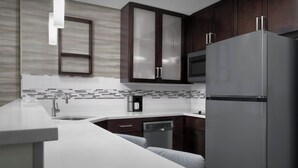 A modern kitchen with dark wooden cabinets, a stainless steel refrigerator, a microwave, and a dishwasher. - Residence Inn by Marriott Jacksonville South/Bartram Park (Jacksonville)