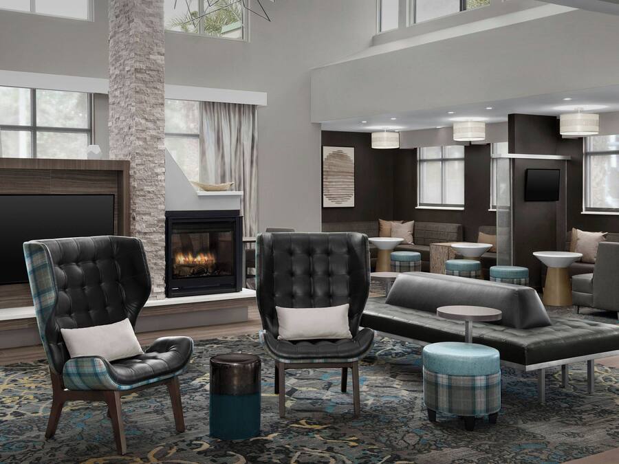 A modern living room with a fireplace, leather armchairs, a sofa, and ottomans.