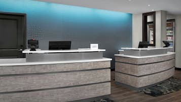 A reception desk with a digital screen, a computer, and a sign that reads 'Marriott Bonvoy.'