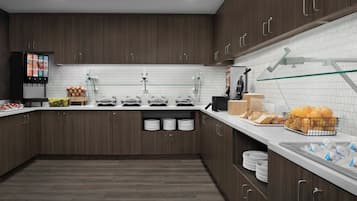Een moderne keuken met donkerhouten kastjes, een witte betegelde spatwand en een vitrinekast met glazen deuren.