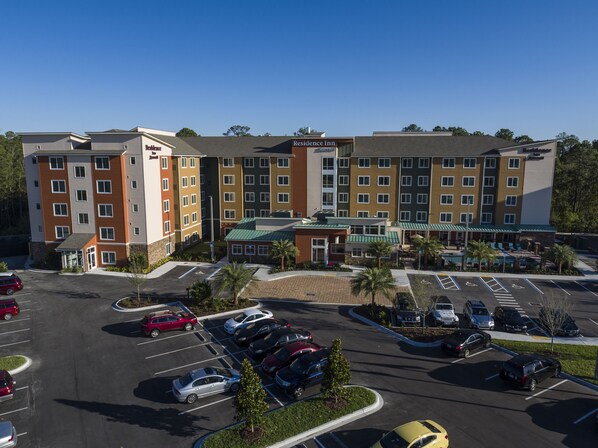 A multi-story hotel with a parking lot and several cars.