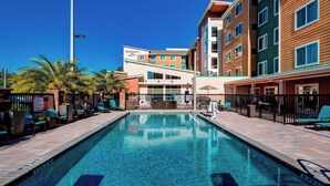 A swimming pool with lounge chairs and a building with multiple floors and balconies. - Residence Inn by Marriott Jacksonville South/Bartram Park (Jacksonville)