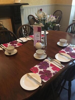 A dining table set for a meal with plates, cutlery, and a vase of flowers. - The Claremont (Woodhall Spa)