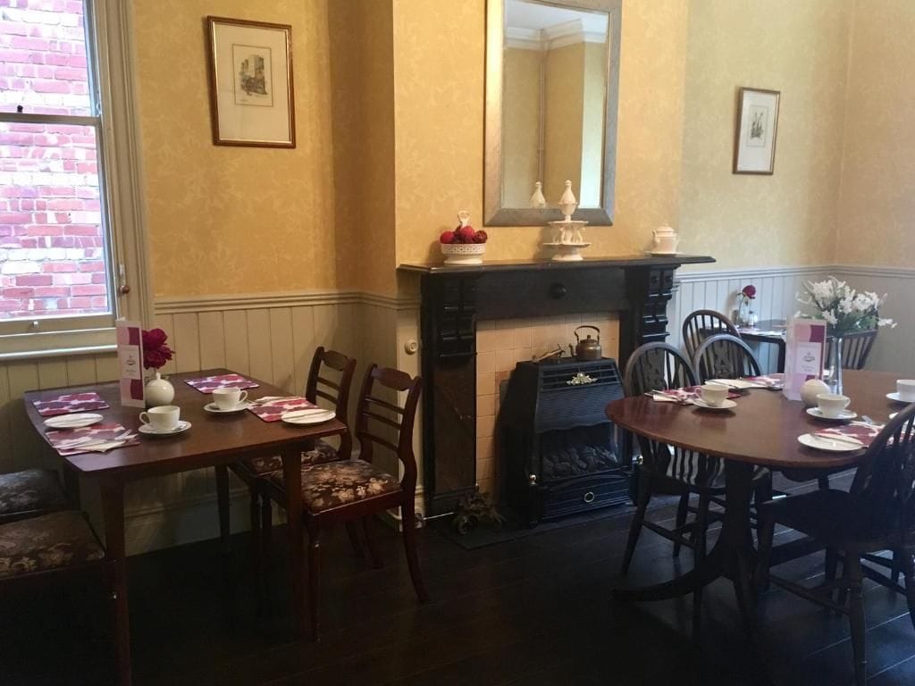 A dining area with a fireplace, wooden furniture, and a brick wall.