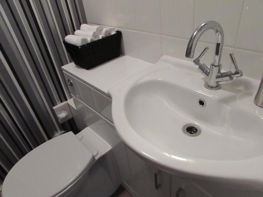 Ein Badezimmer mit einem weißen Waschbecken, einer Toilette und einem schwarzen Handtuchhalter.