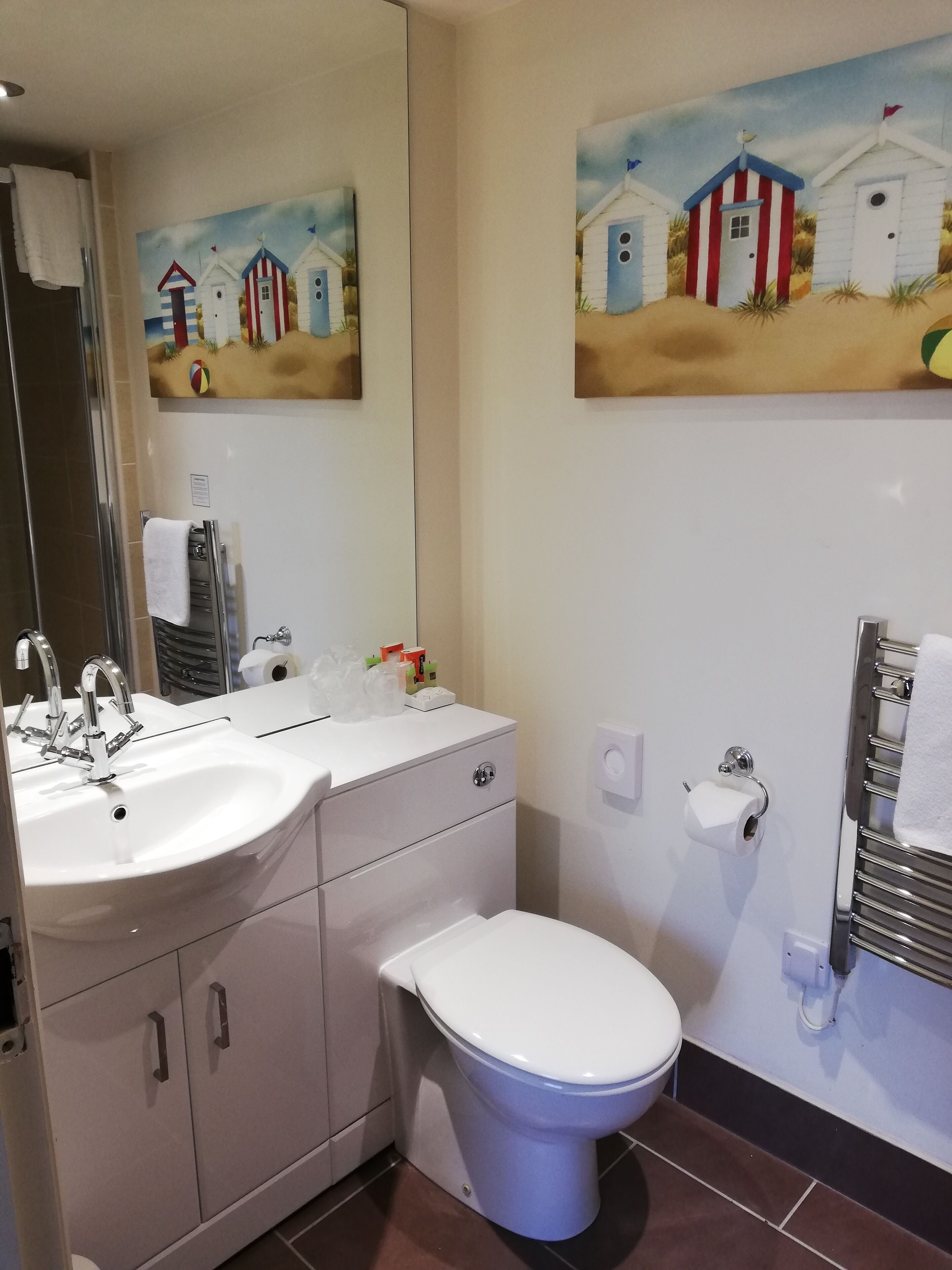 A bathroom with a white sink, two cabinets, a toilet, and a towel rack.