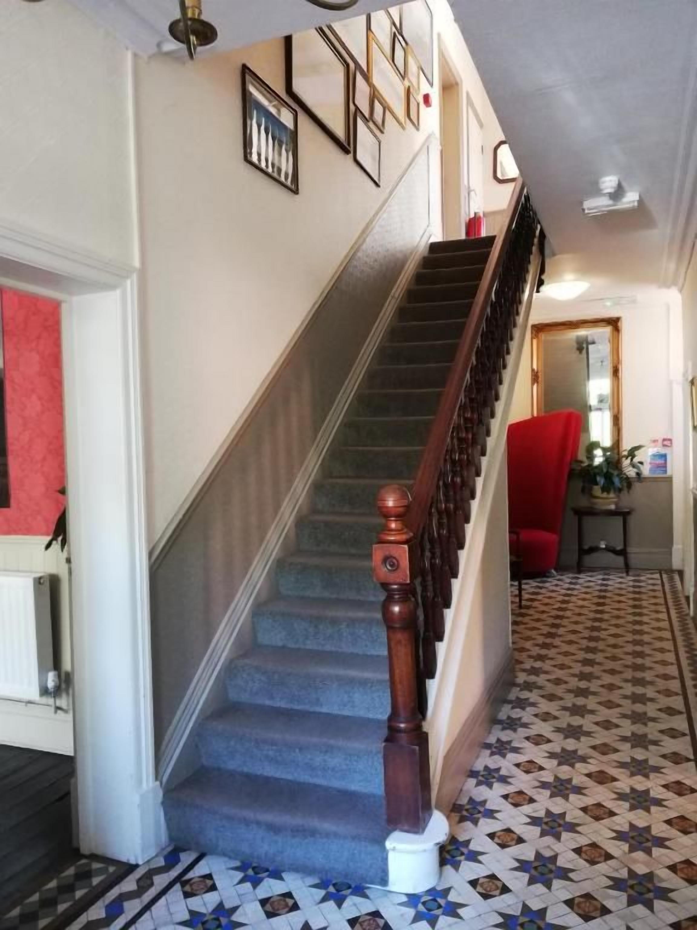 A staircase with a wooden handrail and carpeted steps leading to a landing.