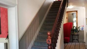 A staircase with a wooden handrail and carpeted steps leading to a landing.