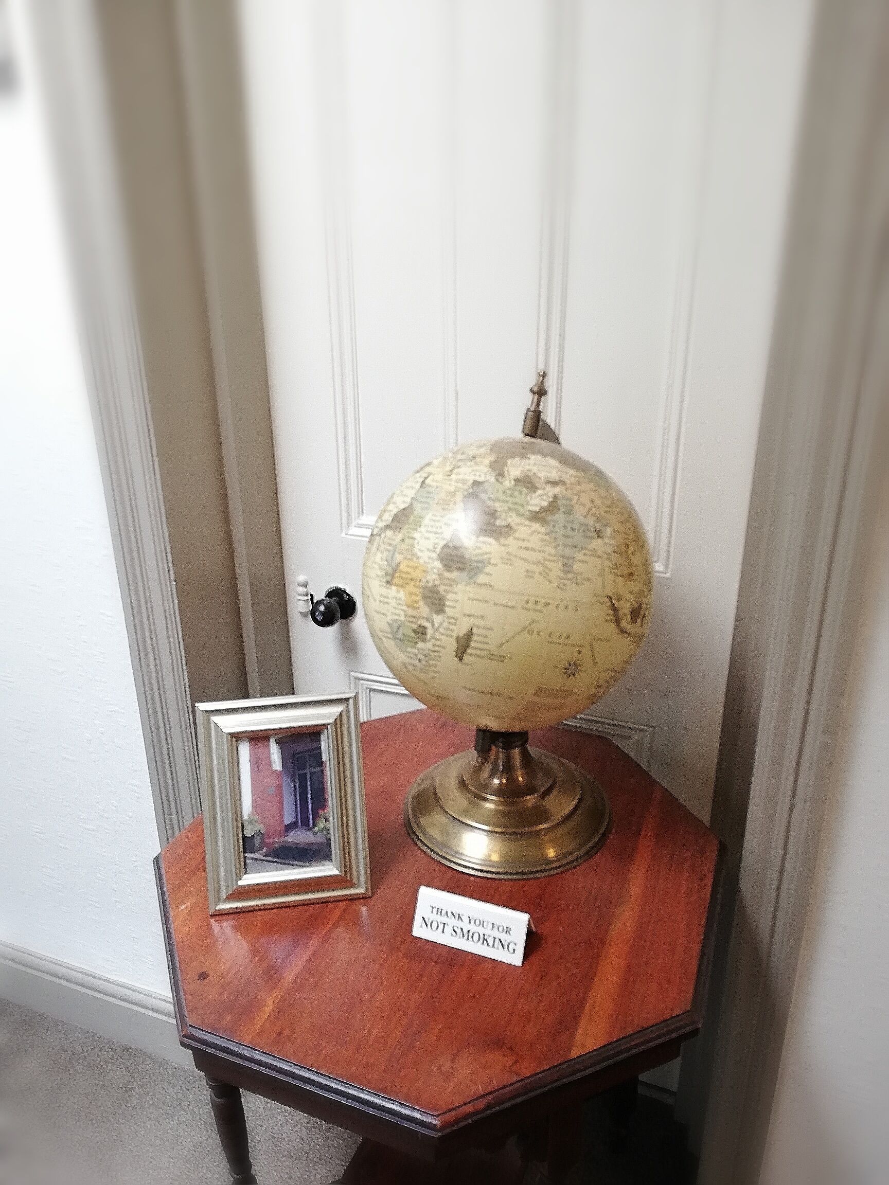 A globe on a wooden stand with a 'Thank you for not smoking' sign.
