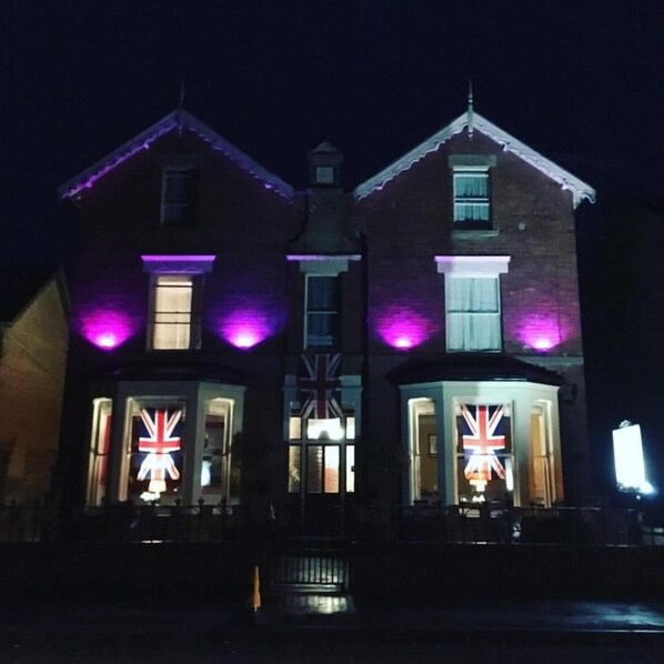 A building with two prominent windows featuring the Union Jack flag. - The Claremont (Woodhall Spa)