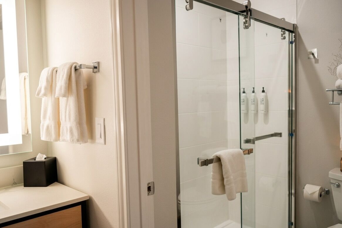 Un bagno moderno con cabina doccia in vetro, un water e un angolo lavabo con asciugamani.