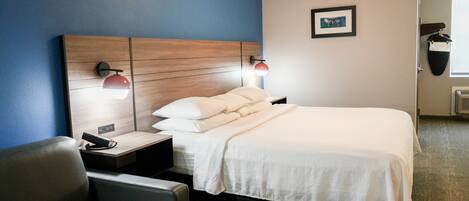 Habitación de hotel con cama, mesitas de noche, escritorio, silla y un cuadro colgado en la pared.