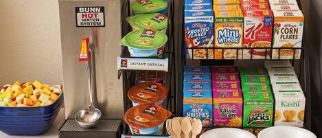 A self-serve breakfast station with instant oatmeal, various cereals, and Quaker Oats products.